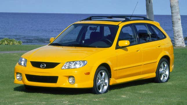 A photo of a yellow Mazda Protege5 near the sea. 