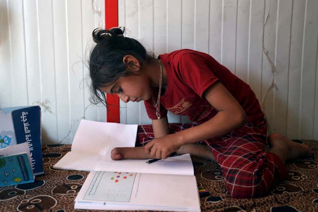 Doaa al-Hassan, 10 years old, who lost her hand to a cluster bomb in 2022, studies at a camp near the town of Ain Sheeb, northern Idlib province, Syria, on July 18, 2023. More than 300 people were killed by cluster munitions in Ukraine in 2022, according to an international watchdog, displacing Syria as the country with the highest number of deaths from the controversial weapons for the first time in a decade. (AP Photo/Omar Albam)