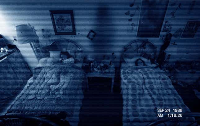 Two characters from Paranormal Activity 3, sleeping while a shadow stands between them in their room. 
