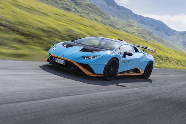 A light blue and orange Lamborghini Huracan STO drives on a mountain road