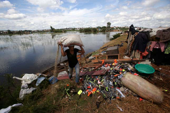 A man caries belongings from his house destroyed by tropical storm Ana in Antananarivo, Madagascar, Wednesday, Jan. 26.