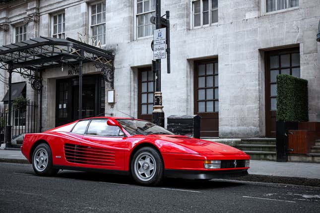 Una foto de un Testarossa rojo estacionado en la calle con sus extraños espejos retrovisores altos