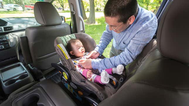 A photo of a person buckling a baby into a rear facing car seat