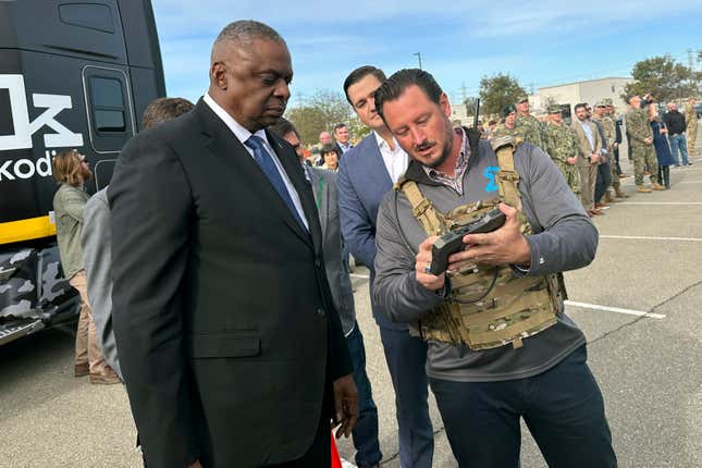 Defense Secretary Lloyd Austin takes a closer look at the device used to control a swarm of drones that lifted off from a parking area at the Defense Innovation Unit in Mountain View, Calif, on Friday, Dec. 1, 2023. Austin is in California for meeting with defense ministers from Australia and the United Kingdom, but took some time to see several projects under development at DIU. (AP Photo/Lolita Baldor)