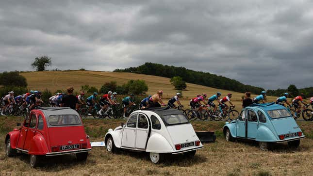 A photo of three Citroën 2CV at the side of the Tour de France route. 