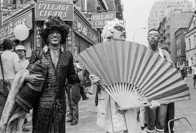 L’activiste américaine de libération des homosexuels Marsha P. Johnson (1945-1992, au centre gauche, en tenue sombre et cheveux noirs), avec d’autres personnes non identifiées, au coin de Christopher Street et de la 7e Avenue pendant la marche des fiertés (plus tard la marche des fiertés LGBT), New York, New York, 27 juin 1982. 