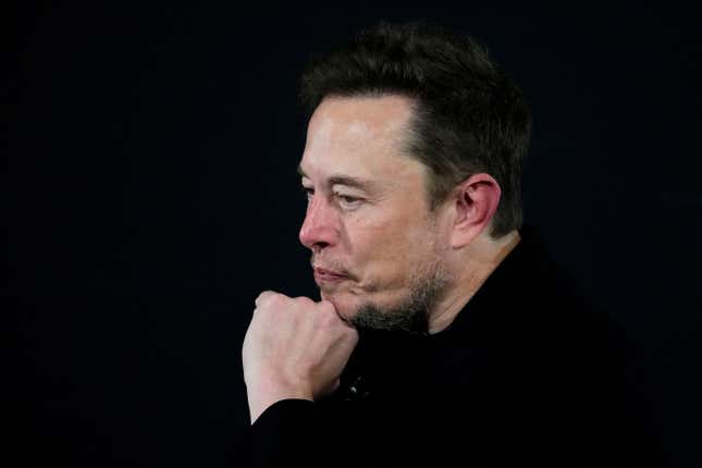 close-up of Elon Musk in a black, long-sleeve T-shirt, who has his head resting on his left fist