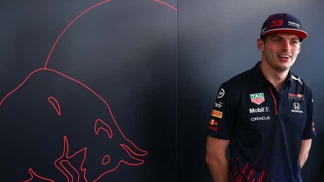 Max Verstappen smiles in front of a Red Bull logo 