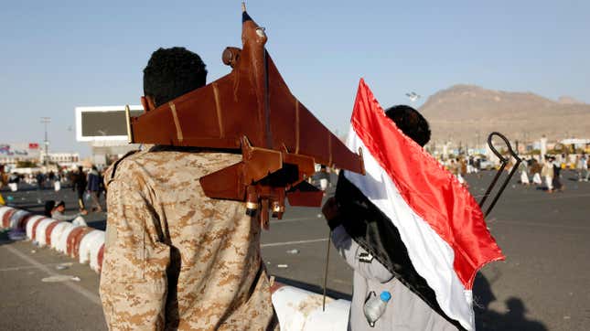 Un hombre que sostiene la bandera nacional de Yemen y otro que lleva un jet simulado protestan contra los ataques aéreos de Estados Unidos y el Reino Unido en la capital, Saná.