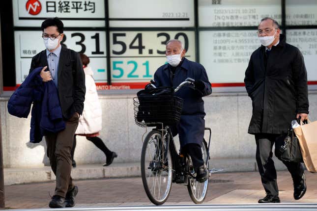 People walk in front of an electronic stock board showing Japan&#39;s Nikkei 225 index at a securities firm Thursday, Dec. 21, 2023, in Tokyo. Asian shares fell Thursday after Wall Street hit the brakes on its big rally following disappointing corporate profit reports and warnings that the market had surged too far, too fast.(AP Photo/Eugene Hoshiko)