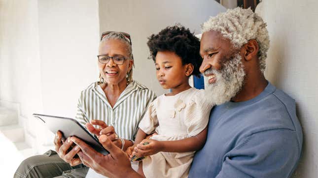 Grandfather, grandmother reading to their grandchild
