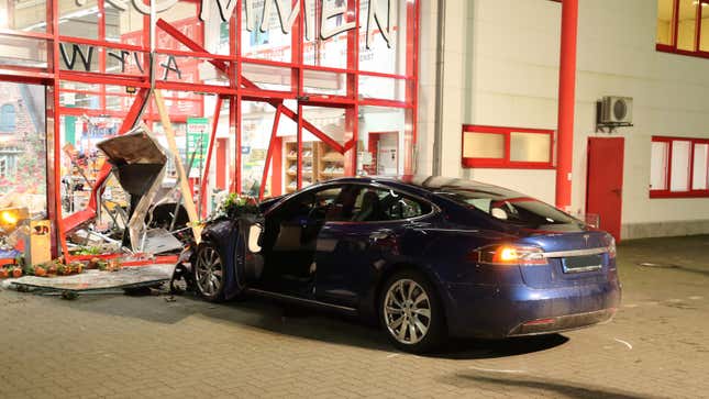 A photo of a Tesla car crashed into a building. 