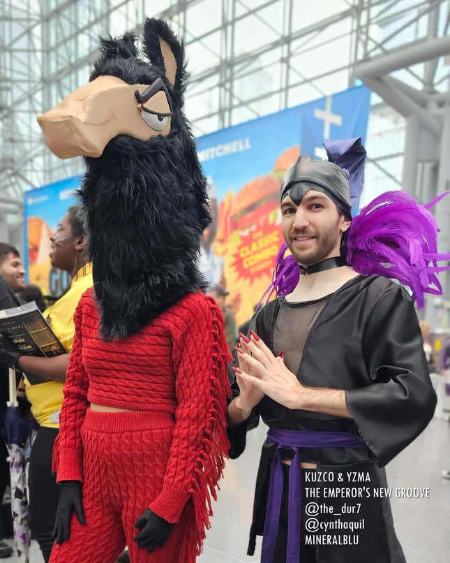 A cosplayer dressed as Kuzco in llama form (complete with a knit two-piece outfit) and one dressed as Yzma look into the camera. 