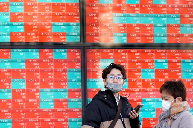 FILE - People stand in front of an electronic stock board showing Japan&#39;s stock prices at a securities firm Monday, Feb. 26, 2024, in Tokyo. Asian markets retreated Friday, March 15, with Hong Kong’s benchmark falling nearly 2%, after a mixed batch of data on the U.S. economy dashed hopes that easier interest rates are coming soon.(AP Photo/Eugene Hoshiko, File)