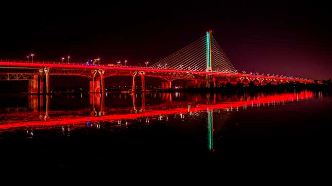 A photo of a suspension bridge in Canada illuminated in red. 