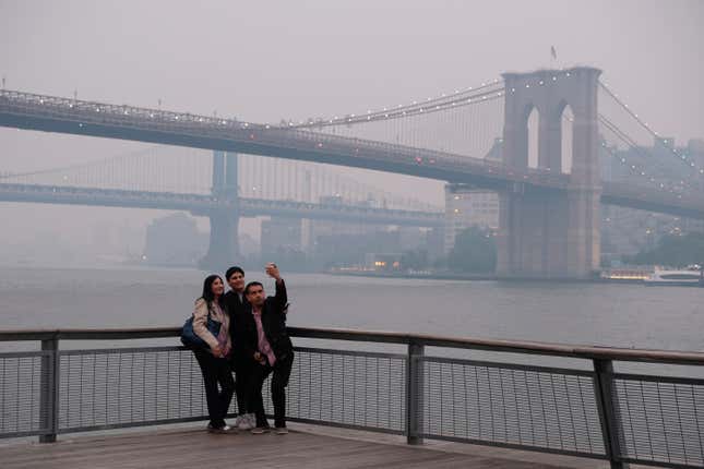 Un grupo se toma una selfie con el fondo del Puente de Manhattan y el Puente de Brooklyn, a la derecha, en Nueva York el miércoles 7 de junio.  2023