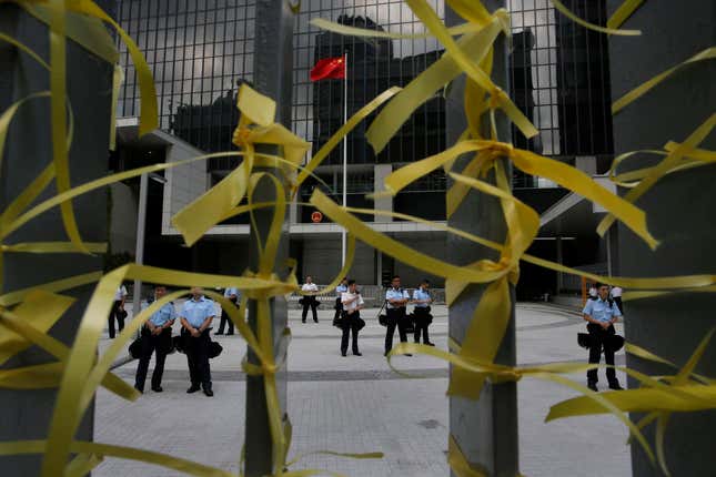 Police officers stand guard against yellow ribbons tied by protesters inside the government headquarters in Hong Kong today.