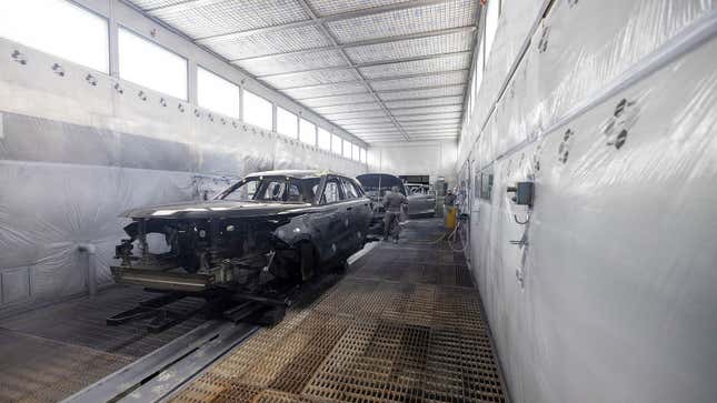 A photo of cars being painted at a factory. 