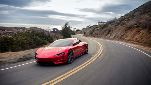 A photo of a red Tesla Roadster driving on a highway. 