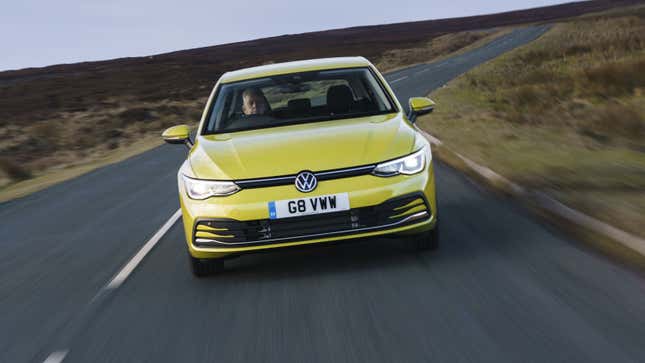 A photo of a yellow-colored VW Golf driving on a country road. 