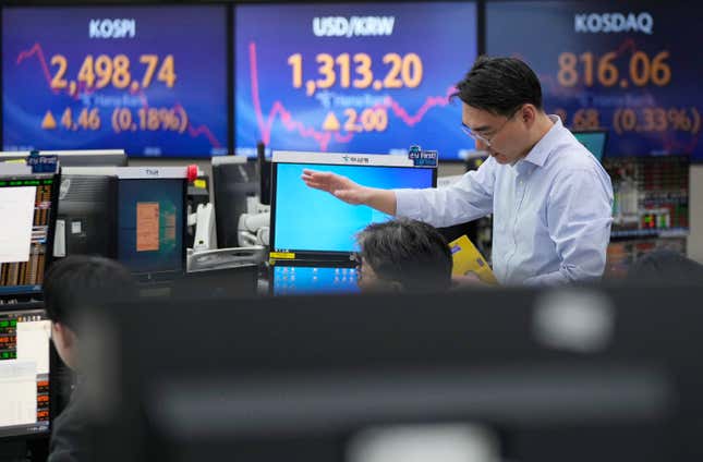 A currency trader gestures near the screens showing the Korea Composite Stock Price Index (KOSPI), left, and the foreign exchange rate between U.S. dollar and South Korean won, center, at the foreign exchange dealing room of the KEB Hana Bank headquarters in Seoul, South Korea, Wednesday, Dec. 6, 2023. Asian shares advanced on Wednesday after most stocks slipped on Wall Street following a mixed set of reports on the U.S. economy. (AP Photo/Ahn Young-joon)