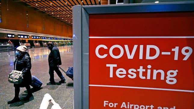 Travelers pass a sign near a COVID-19 testing site in Terminal E at Logan Airport, on Dec. 21, 2021, in Boston 