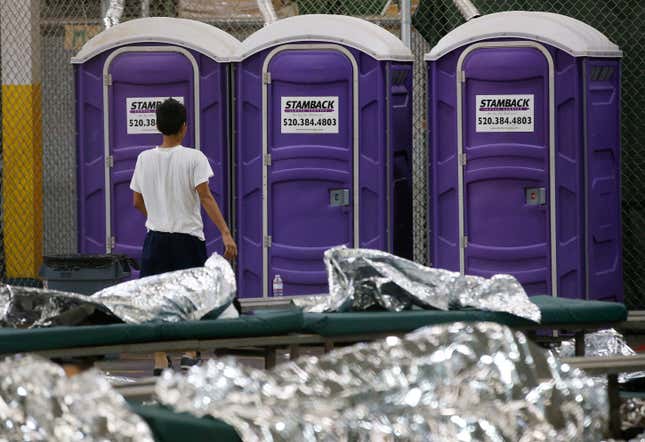 A young boy walks over to use the toilet while in his holding area.