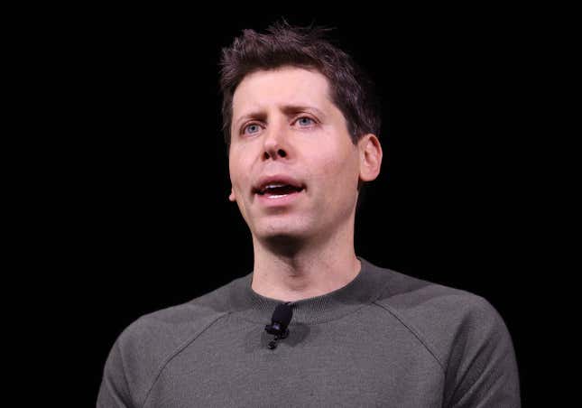 Close up of Sam Altman speaking, his mouth is open, the background is all black, he is wearing a dark grey shirt and there is a lav mic on his collar