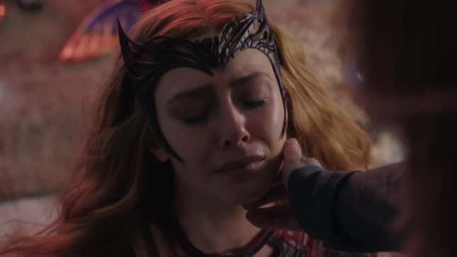 The Scarlet Witch sits close-eyed on the floor while someone caresses her cheek.