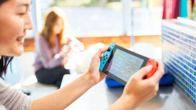 A person is shown playing a Nintendo Switch in handheld mode.