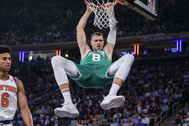 Oct 25, 2023; New York, New York, USA; Boston Celtics center Kristaps Porzingis (8) hangs on the rim after a dunk in the first quarter against the New York Knicks at Madison Square Garden.