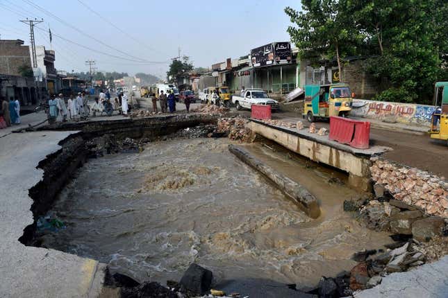 Residents gather beside a road damaged by flood waters following heavy monsoon rains in Charsadda district of Khyber Pakhtunkhwa on August 29, 2022. 