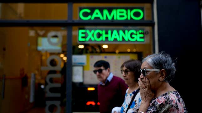 FILE - Pedestrians walk past a money exchange shop in Buenos Aires, Argentina, Oct. 10, 2023. Argentina&#39;s new economy minister said in a televised message on Tuesday, Dec. 12, the Argentine peso will be devalued by 50% from 400 to the U.S. dollar to 800 pesos to the dollar (AP Photo/Natacha Pisarenko, File)