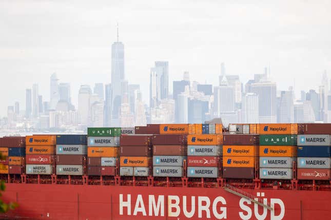 Colorful stacked shipping containers in front of a city skyline