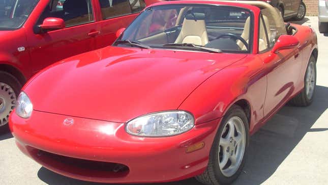 Un Mazda MX-5 Miata rojo de 1999-2000 fotografiado en el Salón del Automóvil Británico Hudson de 2008