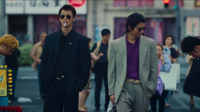 A still of Amazon's Like a Dragon: Yakuza, showing two characters in shades walking through the streets of Kamurocho confidently. Onlookers seem to bowing to them.