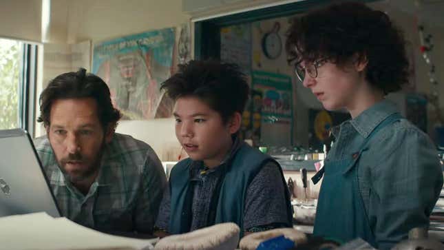 Ghostbusters: Afterlife stars stare at a laptop playing an old commercial for the team from left to right: Paul Rudd, Logan Kim, and Mckenna Grace.
