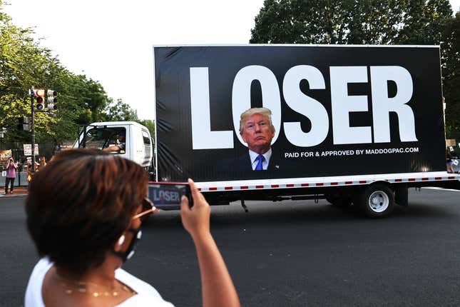 WASHINGTON, DC - AUGUST 27: Joy Jackson photographs a passing truck bearing an image of U.S. President Donald Trump in front of block letters reading “LOSER” at Black Lives Matter plaza August 27, 2020 in Washington, DC. Protesters gathered as the Republican National Convention on its final night was set to nominate Trump for a second term. 