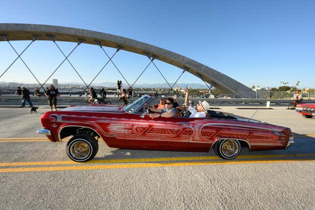 Ornate red Chevy Impala convertible from the 1960s cruising along the sixth street bridge in Los Angeles