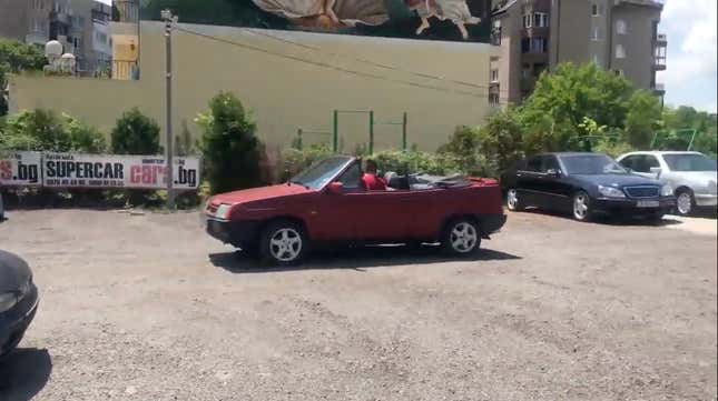 A red Lada Samara cabriolet in a gravel parking lot