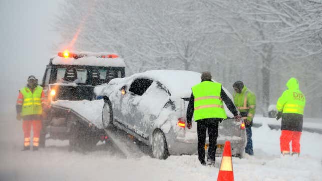 A tow truck picks up a stranded car in the snow 