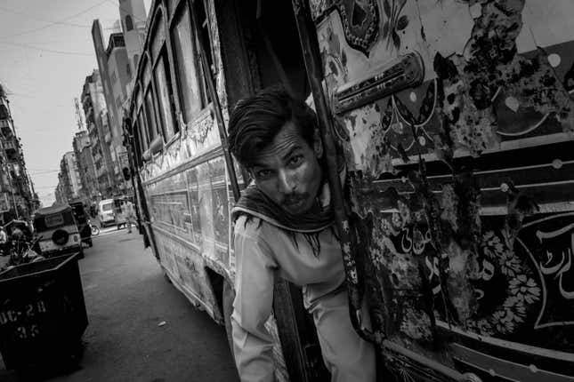 A conductor reaches out for a pose from one of Karachi’s uniquely decorated local buses, but with a new public transit programme in the works, including a shiny new bus service, these cultural icons may also disappear.