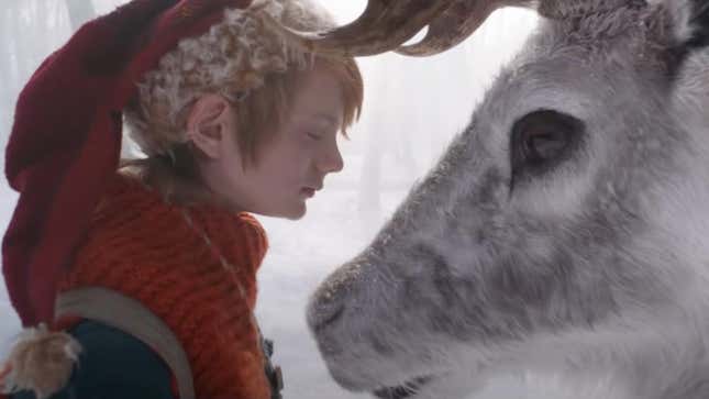 A little boy in a red stocking cap closes his eyes as he meets a reindeer in a scene from Netflix holiday fantasy A Boy Called Christmas.