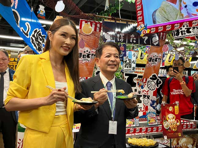 Japanese Agriculture Minister Ichiro Miyashita, right, and Malaysian celebrity Amber Chia attend an event at Japanese store, Don Don Donki in Kuala Lumpur Wednesday, Oct. 4, 2023 to promote the safety and deliciousness of Japanese scallops to shoppers. Japan hopes to resolve the issue of China's ban on its seafood within the scope of the World Trade Organization ambit and will hold food fairs overseas to bolster seafood exports amid safety concerns over the release of treated water from the Fukushima Daiichi nuclear plant, Miyashita said Wednesday. (AP Photo/Eileen Ng)