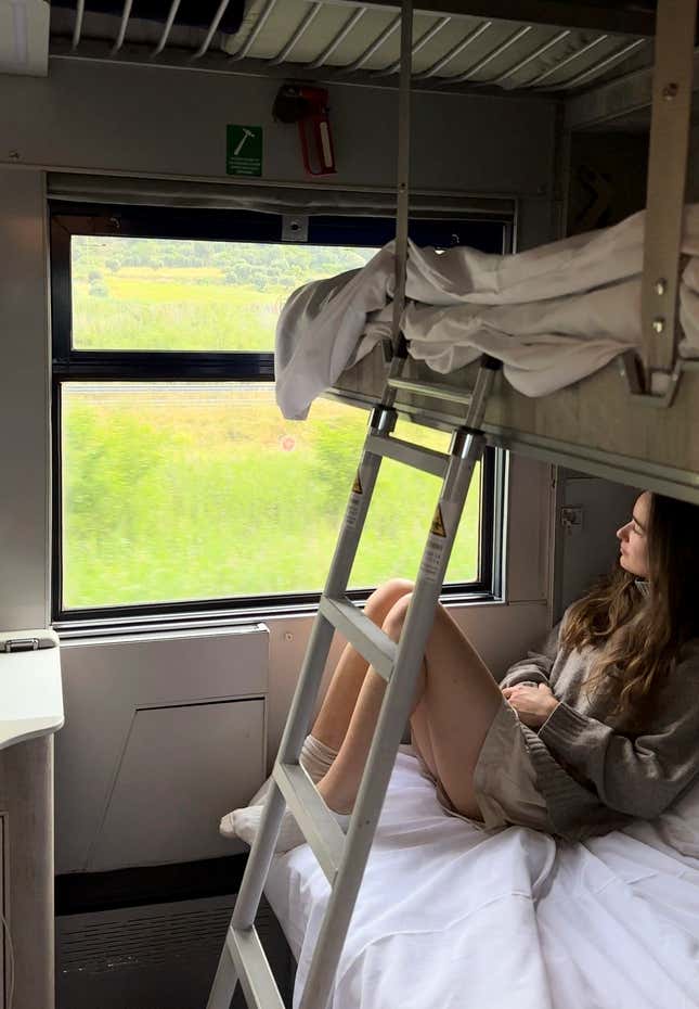 Sarah Marks, of London, looks out at the Italian countryside on TrenItalia&#39;s Intercity Notte sleeper train from Palermo to Rome, on June 10, 2023. A growing number of climate-conscious Europeans are giving up flying in favor of long-haul trains. (Sarah Marks via AP)