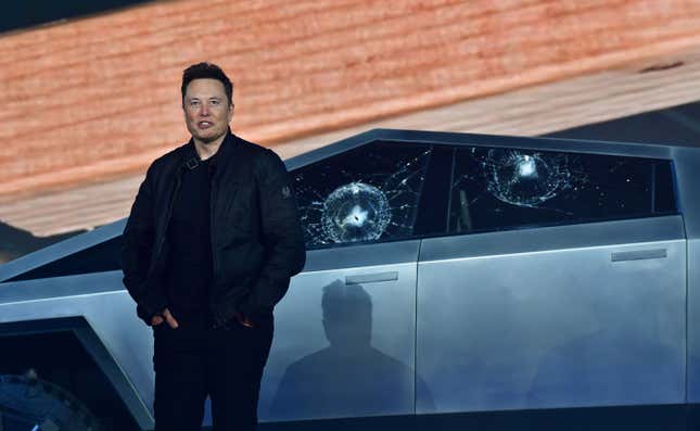 Elon Musk standing in front of the Cybertruck with broken windows.