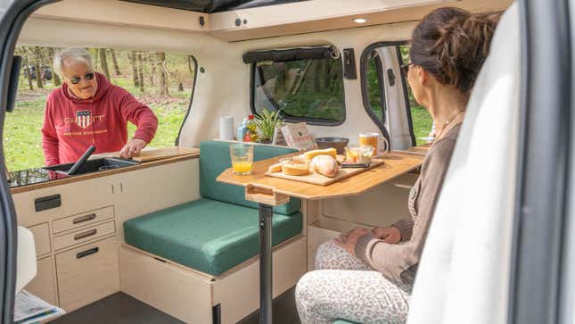 A photo of two people sat in an electric camper.