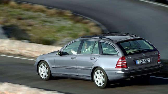 a rear 3/4 image of a grey C-Class wagon driving down a road