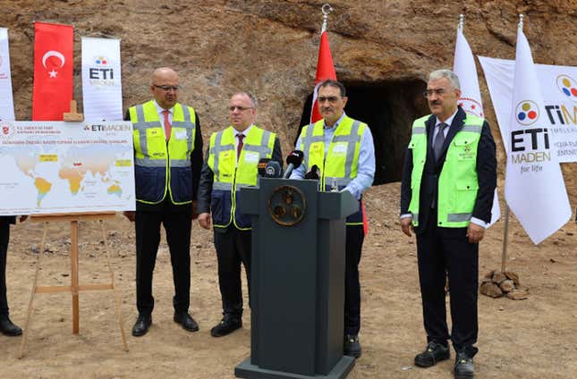 Four old guys behind a podium and in front of a mine, wearing safety vests