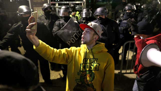 A protester takes a selfie in front of police dispersing the Capitol riot.